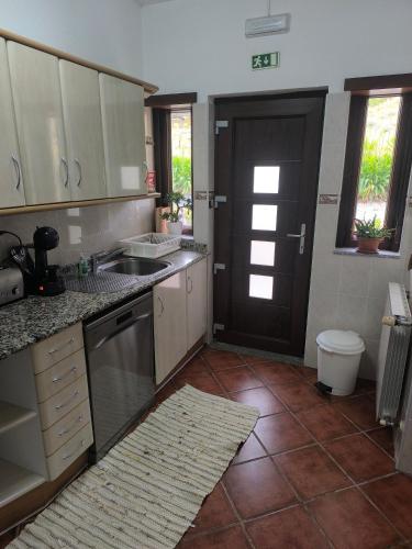 a kitchen with white cabinets and a black door at Quinta do Retiro in Felgar