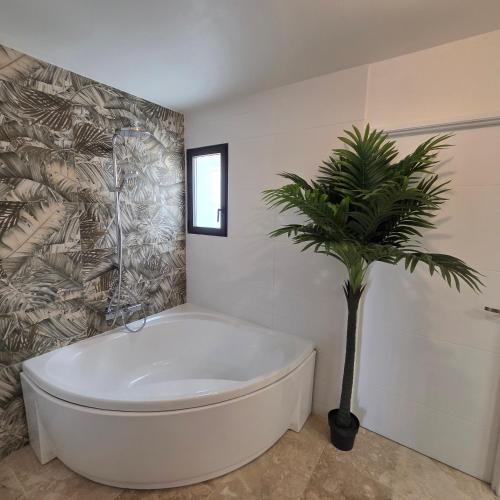 a bathroom with a tub and a palm tree in it at Villa View in Combaillaux