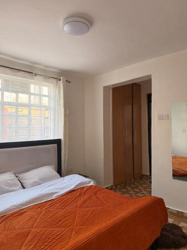 a bedroom with a bed with an orange blanket at 2020 suites utawala in Nairobi