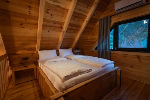 a bed in a log cabin with a window at Alpas forest house in Kuršumlija