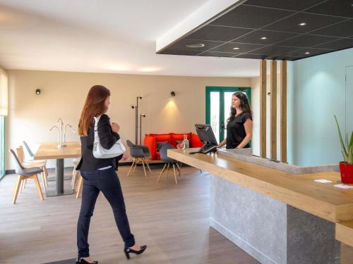 two women walking past a counter in a restaurant at ibis Perpignan Nord Rivesaltes in Rivesaltes