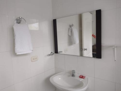 a white bathroom with a sink and a mirror at Finca Hotel Campestre Salitre Villeta in Villeta