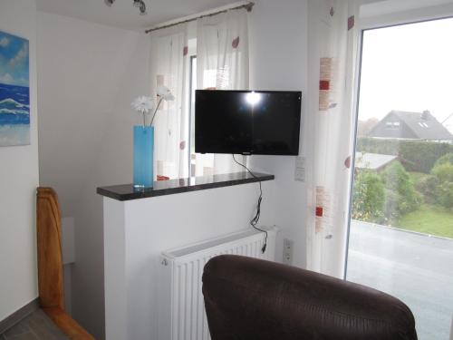 a room with a tv on a wall with a window at Lieblingsplatz in Kappeln