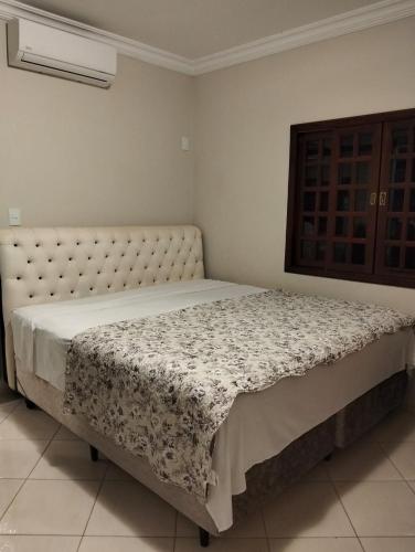 a bedroom with a large bed with a floral blanket at Quarto em Foz, ótima localização em casa familiar in Foz do Iguaçu