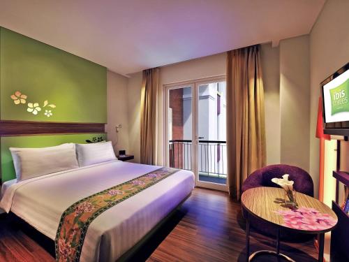 a hotel room with a bed and a table at Ibis Styles Bali Denpasar in Denpasar
