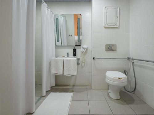 a white bathroom with a toilet and a sink at ibis Mogi das Cruzes Shopping in Mogi das Cruzes