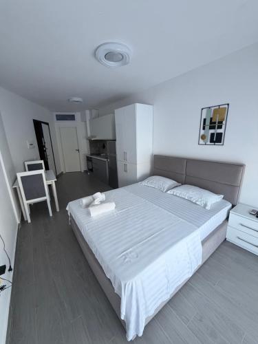 a bedroom with a large white bed and a kitchen at Rei Apartment 2 in Shëngjin
