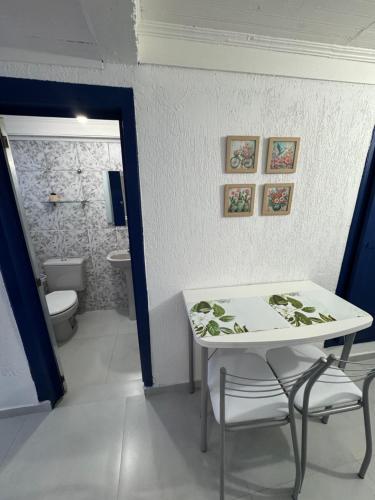 a room with a table and a bathroom with a toilet at Suite Simples PRIVATIVA in Diamantina