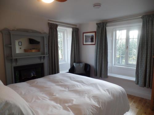 a bedroom with a white bed and a fireplace at Barrowgarth Guest House in Appleby