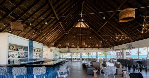 a restaurant with a bar with chairs and tables at Mia Reef Isla Mujeres - All Inclusive Resort in Isla Mujeres