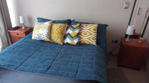 a bed with a blue comforter and pillows at depto nuevo temuco in Temuco