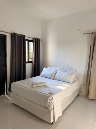 a white bed in a room with a window at Oikos Residencial in Chimoio