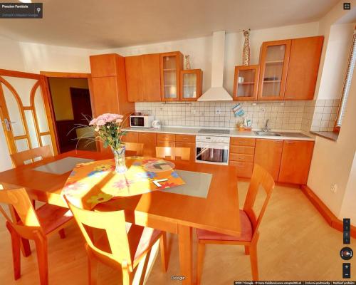 a kitchen with a wooden table and a table and chairs at Penzion Fantazia Poprad - Self check-in in Poprad