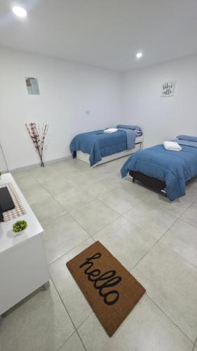 a room with two beds and a welcome mat on the floor at VMV Departamento in Río Grande