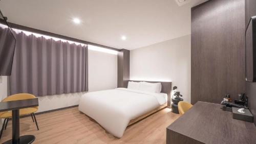 a hotel room with a white bed and a desk at HOTEL lantana in Tudomi