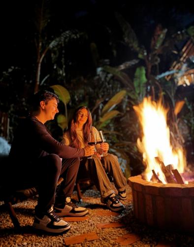 a man and woman sitting next to a fire at Cabana com Cachoeira Privativa in Imaruí
