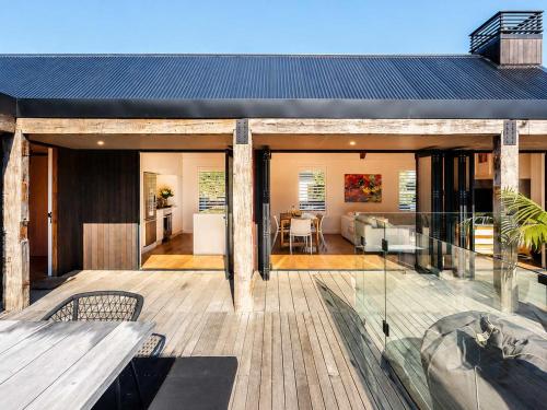 a house with a large deck with a view of a kitchen at Blackpool Boathouse - Stay Waiheke in Oneroa