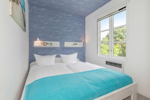 a blue and white bedroom with a bed and a window at Ferienanlage Bansin Seepferdchen 4 in Bansin