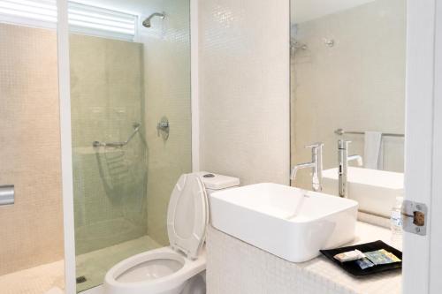 a bathroom with a toilet and a sink and a shower at We Hotel Acapulco in Acapulco