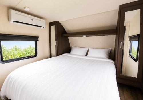 a bedroom with a white bed and a window at NaturalfarmZAMPA in Yomitan