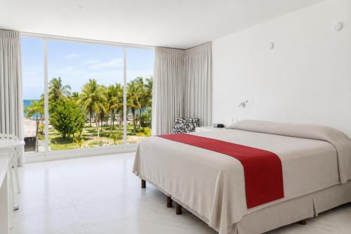 a white bedroom with a large bed and a large window at We Hotel Acapulco in Acapulco