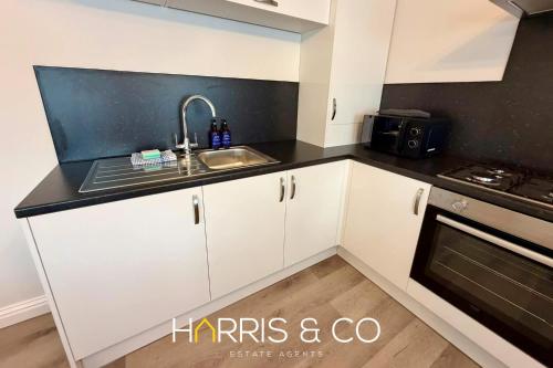 a kitchen with white cabinets and a sink at Upper Marsh Apartment in Thornton