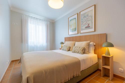 a bedroom with a large white bed with two lamps at Retiro do Livro in Óbidos