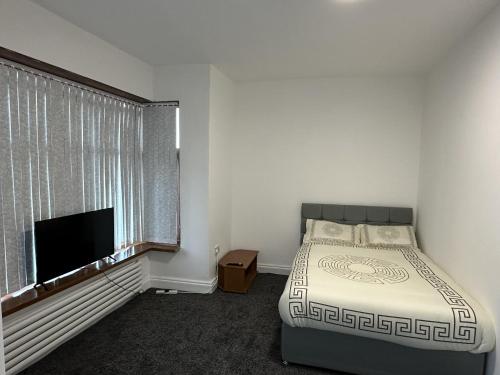 a bedroom with a bed and a flat screen tv at Plus Properties Leeds 3 in Bradford