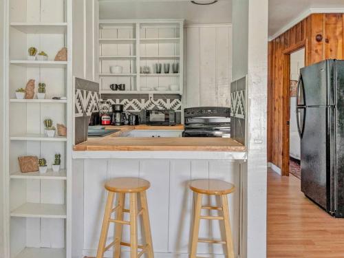 a kitchen with two bar stools and a refrigerator at Pet-Friendly Near Zion & Hot Tub in Downtown Kanab in Kanab