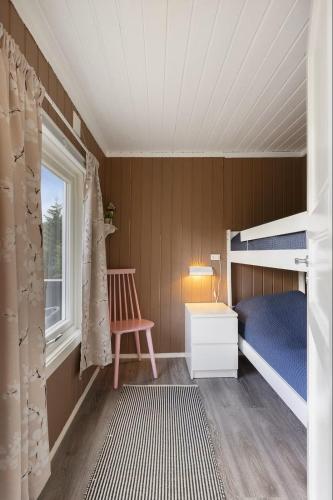 a small bedroom with a bunk bed and a chair at Kvila in Surnadal