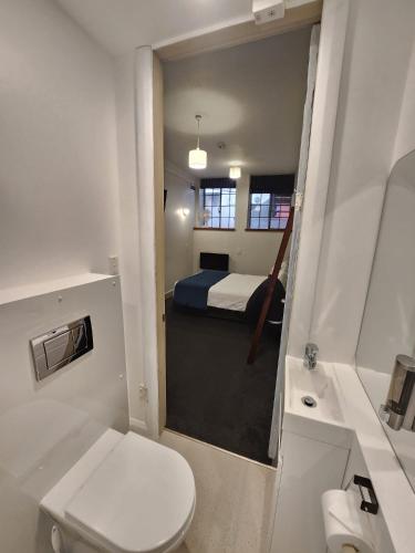 a bathroom with a toilet and a bed in a room at U Boutique Hotel, SureStay Collection by BW in Wellington