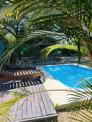 a swimming pool with benches and a palm tree at Cabaña La Churra in Corrientes