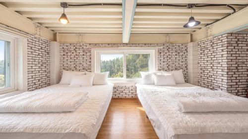 two beds in a room with a brick wall at Gapyeong Ddel Poolvilla in Gapyeong