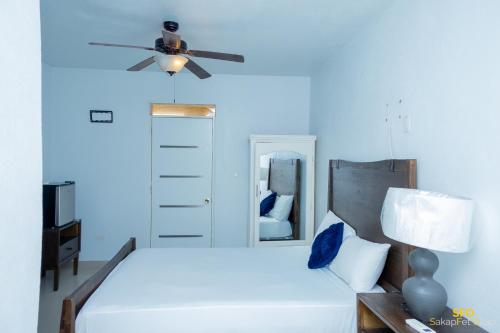 a bedroom with a white bed with a ceiling fan at La Reserve Hotel in Cap-Haïtien