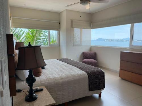 ein Schlafzimmer mit Bett, Stuhl und Fenstern in der Unterkunft Condominio Marlica in Manzanillo