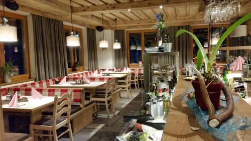 ein Restaurant mit Holztischen und -stühlen und Topfpflanzen in der Unterkunft Gasthof Schütthof in Neukirchen am Großvenediger