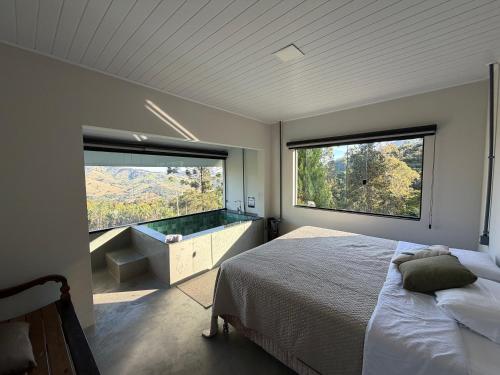 a bedroom with a bed and two large windows at Refúgio Deusmideu in São Bento do Sapucaí