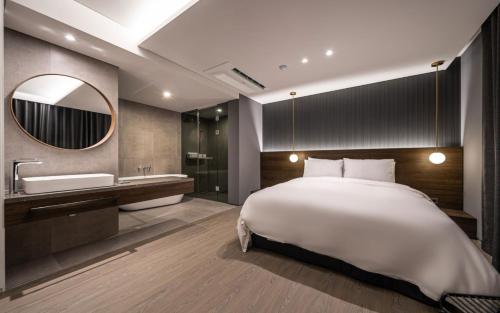 a bedroom with a bed and a sink and a mirror at H hotel Gasan in Seoul