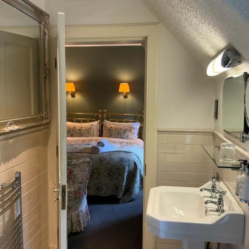 a bathroom with a bed and a sink and a mirror at Corriegour Lodge Hotel in Spean Bridge