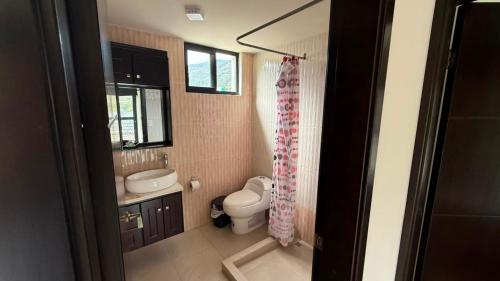 a bathroom with a toilet and a sink and a mirror at Volcán Suits in Baños