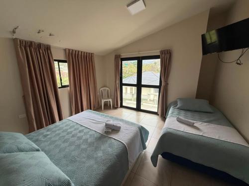 two beds in a room with a window at Volcán Suits in Baños