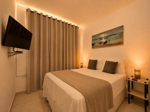 a hotel room with a bed and a flat screen tv at Pousada Bella Boipeba in Ilha de Boipeba