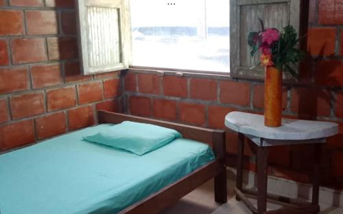 a room with a bed and a table with a vase of flowers at Posada El Encanto in Nuquí