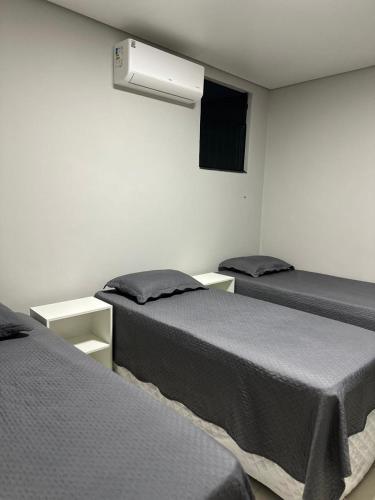 a room with two beds and a television on the wall at Apartamento completo 2 quartos in Brasília