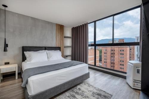 a bedroom with a large bed and a large window at Apartamentos HOUSY Laureles in Medellín