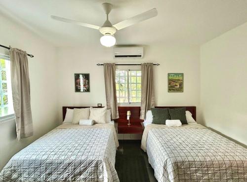 a bedroom with two beds and a ceiling fan at Villa Fidelina Picsina in Río San Juan