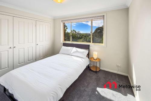 a bedroom with a white bed and a window at Spacious 4-Bedroom Home in Cherrybrook in Cherrybrook
