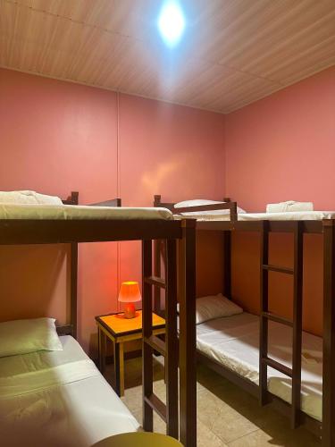 a room with three bunk beds and a table with a lamp at SunriseStay in Panglao Island