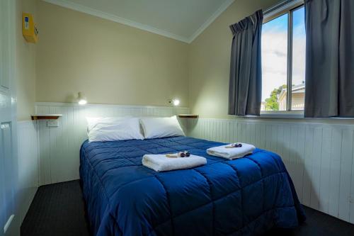 a bedroom with a blue bed with towels on it at Barrack Point Holidays in Barrack Point