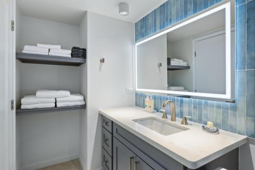 a bathroom with a sink and a mirror and towels at Aston Waikiki Sunset in Honolulu